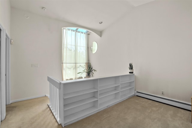 interior space featuring vaulted ceiling, a baseboard heating unit, and light colored carpet