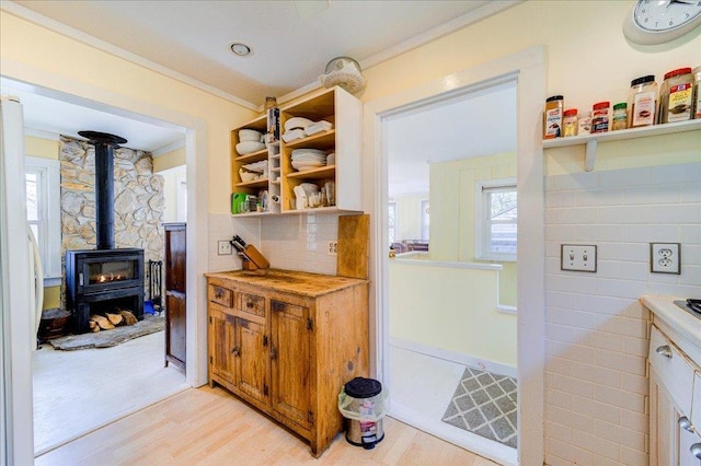 interior space with crown molding, wood finished floors, a wood stove, and tasteful backsplash