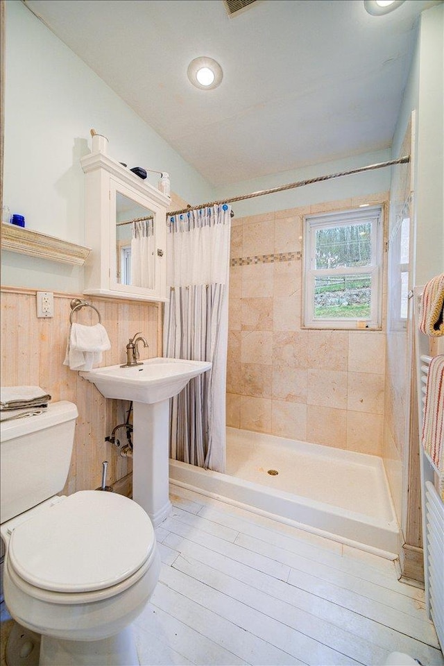 full bath with wainscoting, a stall shower, and toilet