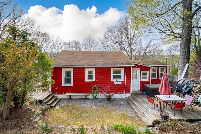 back of house featuring outdoor dining area, a hot tub, and a deck