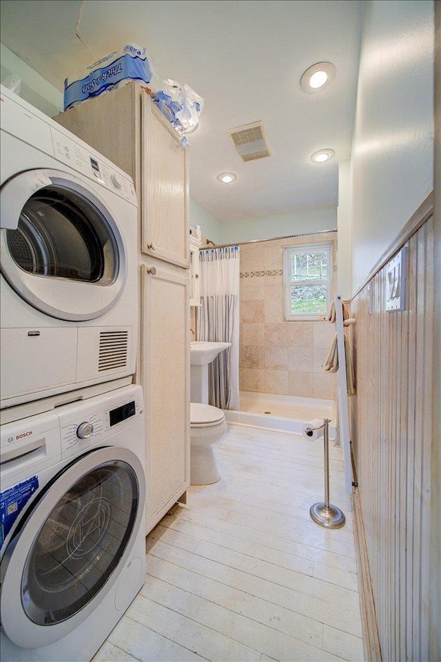 laundry area with stacked washer / drying machine, laundry area, recessed lighting, light wood-type flooring, and visible vents