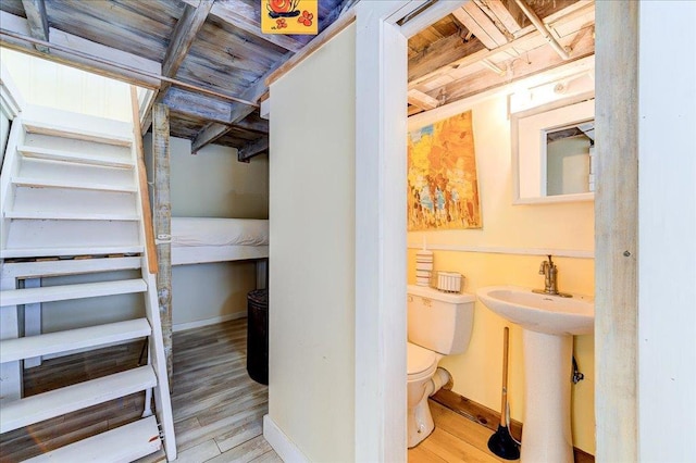 half bath featuring toilet, baseboards, and wood finished floors