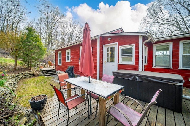deck featuring a lawn, outdoor dining space, and a hot tub