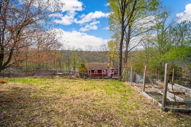 view of yard with fence, a view of trees, and a garden