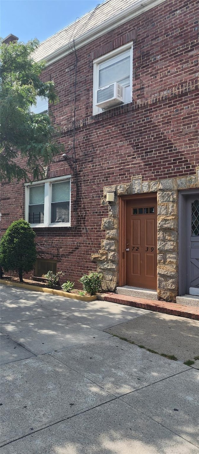 doorway to property featuring cooling unit and brick siding