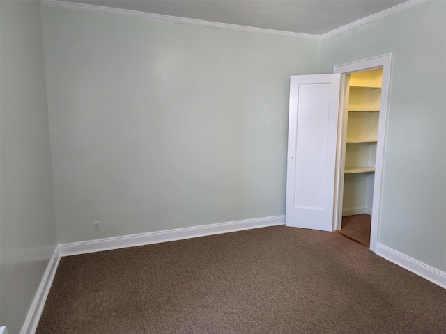 unfurnished bedroom with a walk in closet, crown molding, carpet floors, baseboards, and a closet
