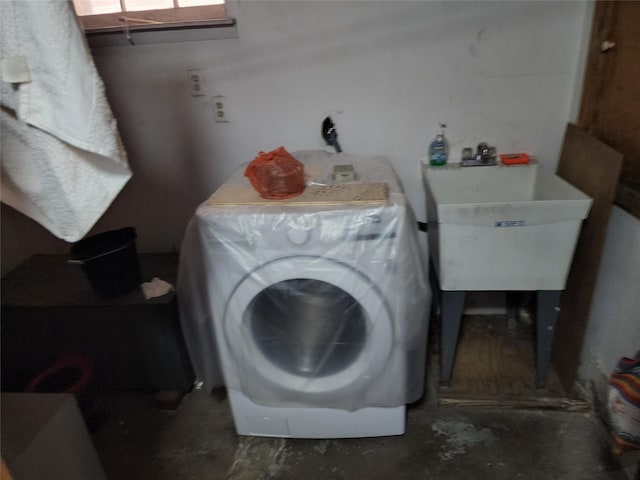 clothes washing area featuring laundry area, a sink, and washer / clothes dryer