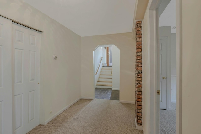 hallway featuring carpet flooring, arched walkways, and baseboards