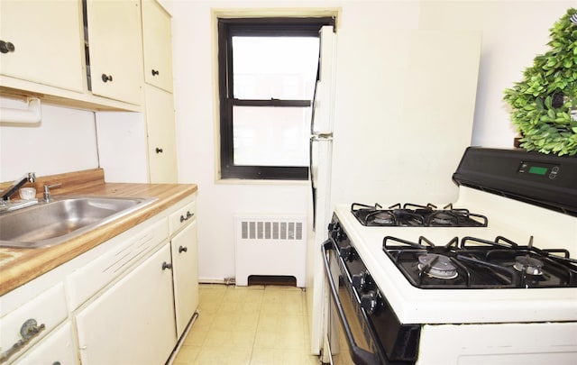 kitchen with a sink, light countertops, radiator, white gas range, and light floors