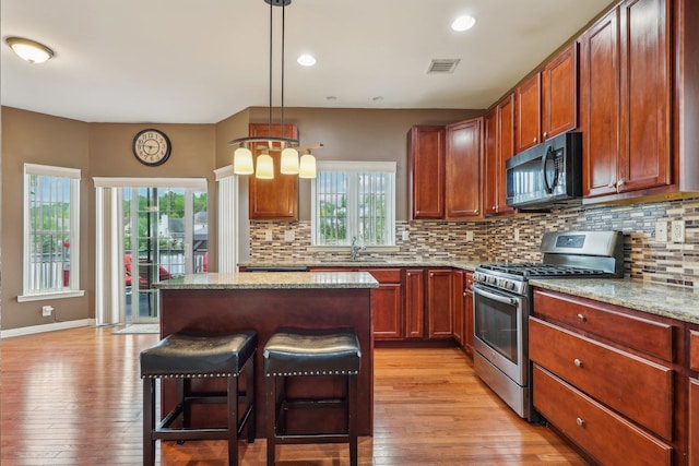 kitchen featuring stainless steel gas range, a sink, light wood-style flooring, plenty of natural light, and recessed lighting
