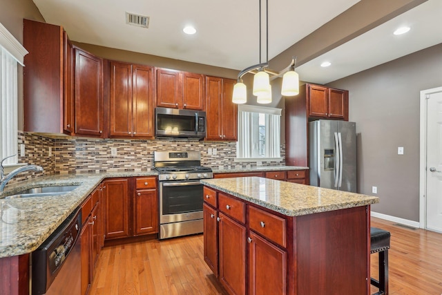kitchen with stainless steel appliances, a sink, light wood-style floors, decorative backsplash, and recessed lighting