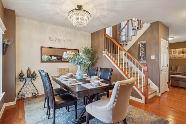 dining area with stairway, wood finished floors, a chandelier, and baseboards