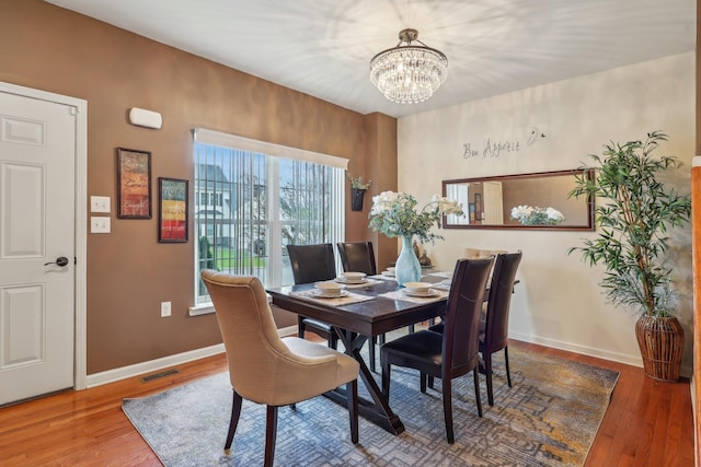 dining room with a chandelier, wood finished floors, and baseboards