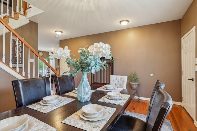 dining room featuring stairs, wood finished floors, and baseboards
