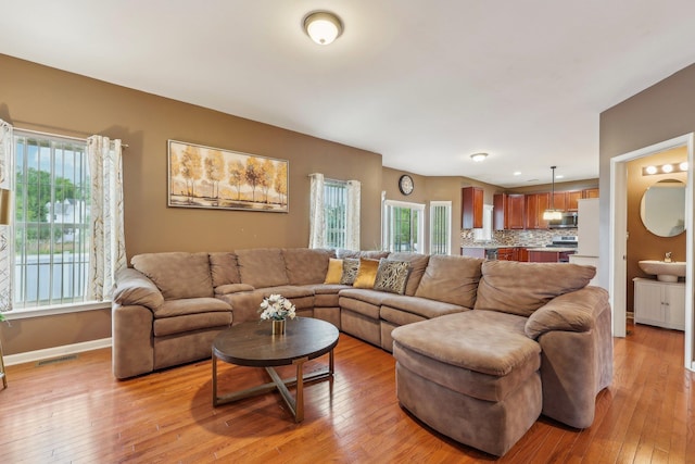 living area featuring plenty of natural light, light wood-style floors, and baseboards