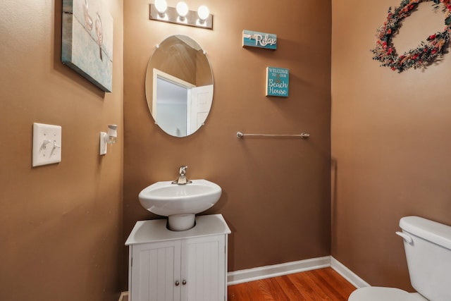 bathroom with wood finished floors, toilet, a sink, and baseboards