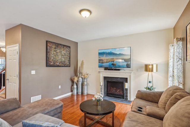 living area featuring wood finished floors, a glass covered fireplace, and baseboards