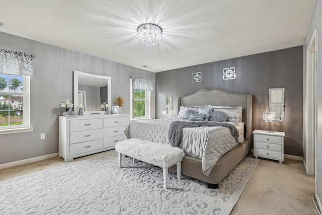 bedroom featuring light colored carpet, a chandelier, and baseboards