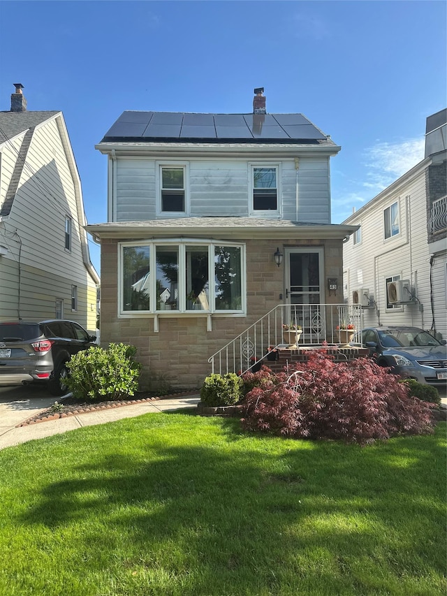 view of front facade featuring a chimney, a front lawn, stone siding, and solar panels