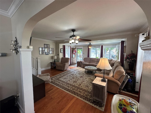 living room with ceiling fan, arched walkways, baseboards, wood finished floors, and ornamental molding
