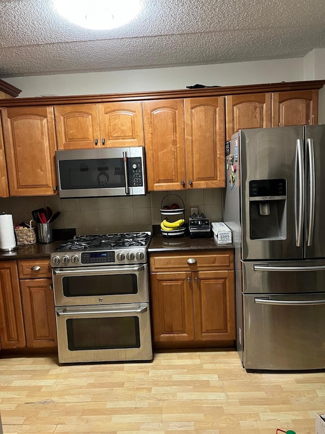 kitchen with brown cabinetry, dark countertops, and stainless steel appliances