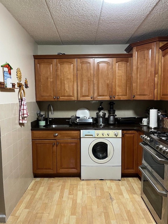 washroom with light wood finished floors, a sink, laundry area, tile walls, and washer / dryer