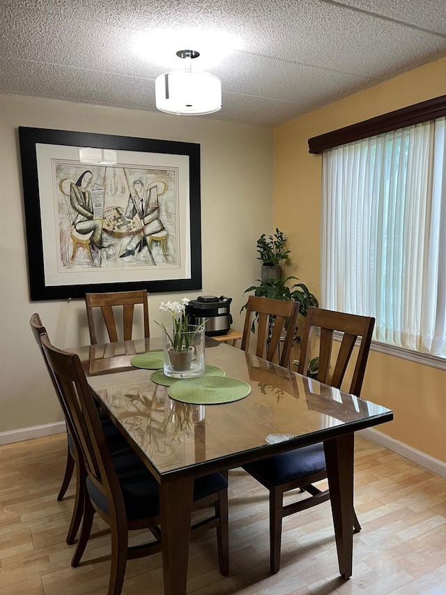 dining space with baseboards and light wood finished floors