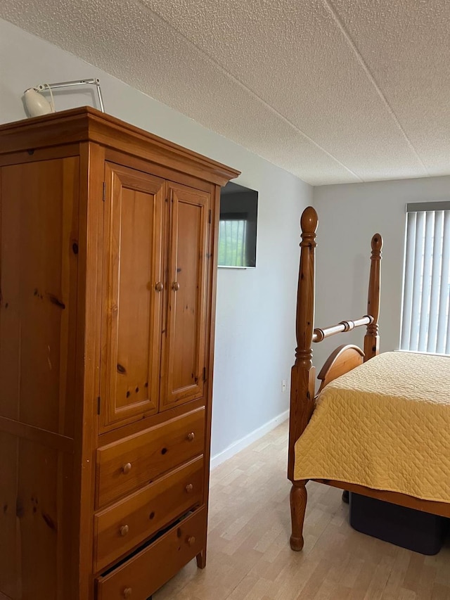 bedroom with multiple windows, light wood-style flooring, and a textured ceiling