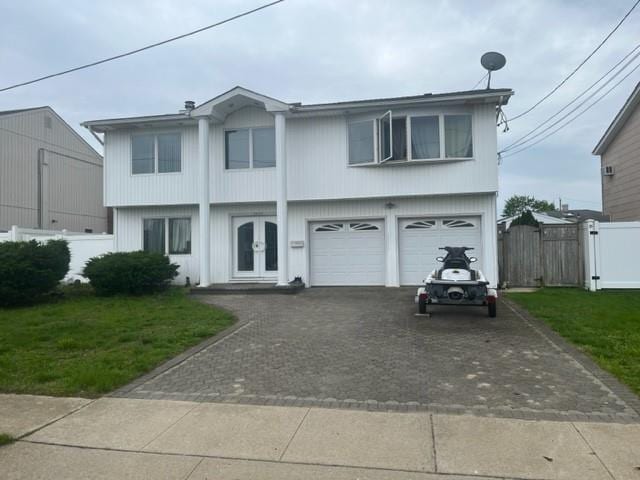 view of front of house with driveway, french doors, an attached garage, and fence