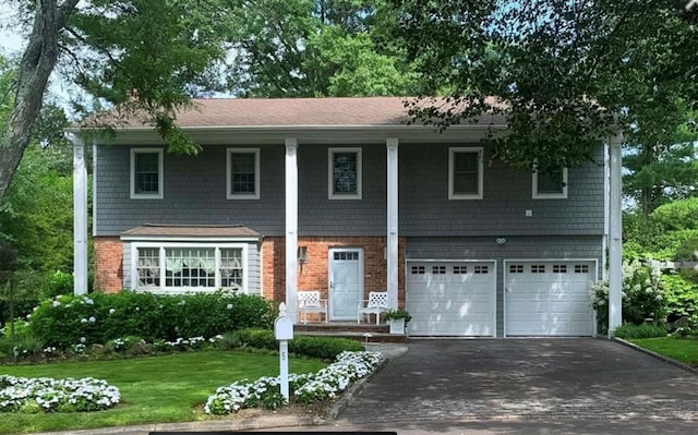 view of front facade with brick siding, an attached garage, a front yard, and aphalt driveway