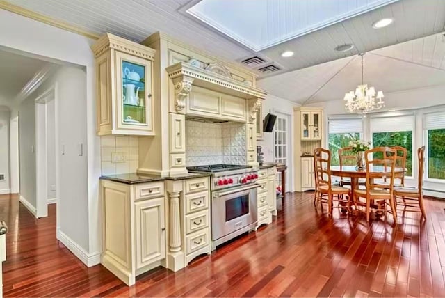 kitchen featuring dark countertops, dark wood-style floors, a chandelier, cream cabinetry, and high end range