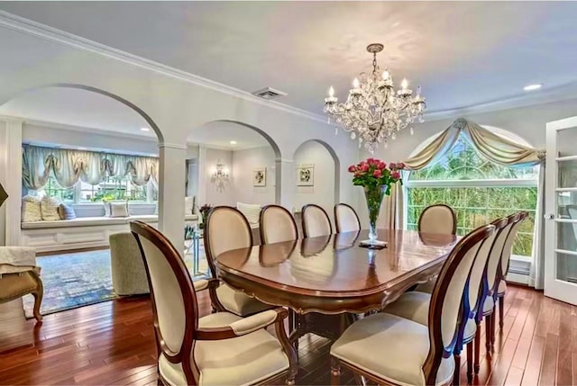 dining room with arched walkways, a notable chandelier, visible vents, and hardwood / wood-style floors