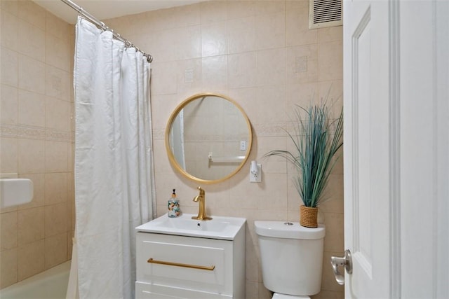 bathroom featuring visible vents, vanity, toilet, tile walls, and shower / bathtub combination with curtain