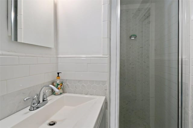 bathroom with vanity, decorative backsplash, a stall shower, and tile walls
