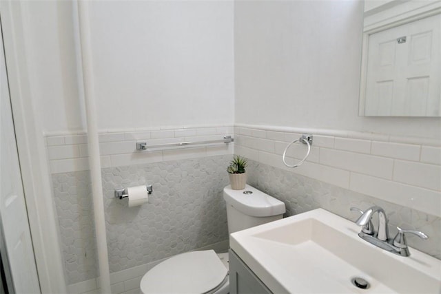bathroom with vanity, toilet, and tile walls