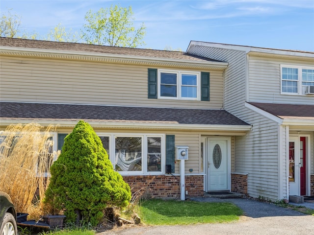 multi unit property with a shingled roof and brick siding
