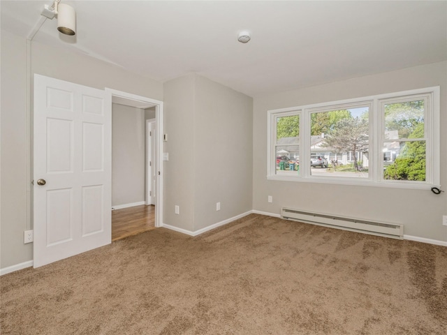 spare room featuring carpet flooring, baseboards, and a baseboard heating unit