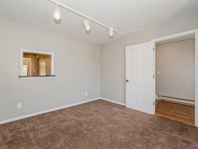 spare room featuring track lighting, baseboards, a baseboard heating unit, and carpet floors