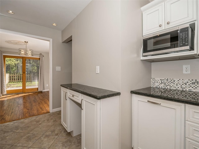 kitchen featuring recessed lighting, baseboards, light tile patterned floors, stainless steel microwave, and white cabinetry