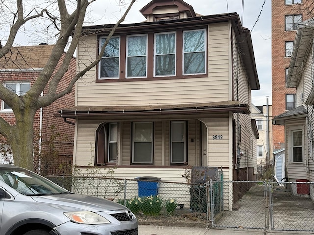 multi unit property with a porch, a gate, and a fenced front yard