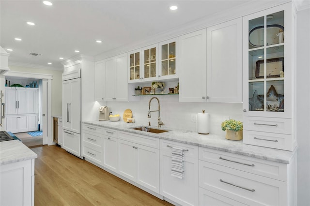 kitchen with white cabinets, crown molding, light wood-type flooring, and a sink