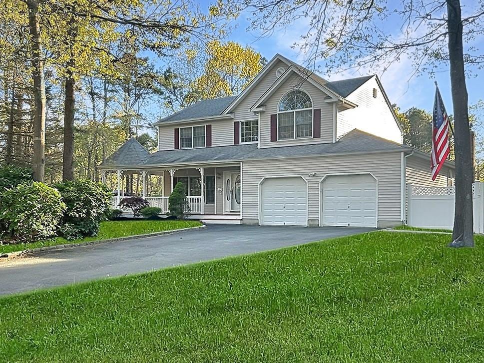 view of front of home featuring a porch, fence, driveway, and a front yard
