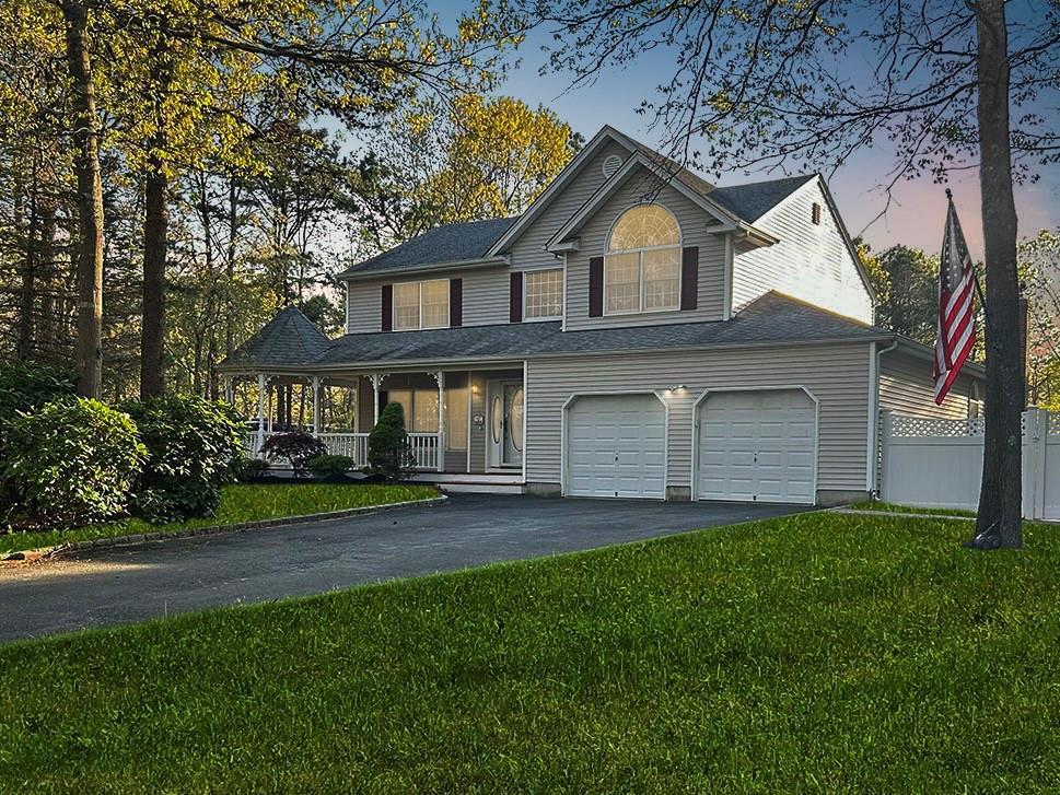 view of front of house featuring a porch, fence, driveway, and a front lawn