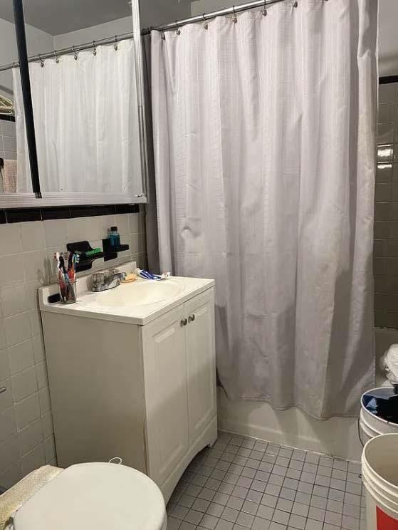 bathroom with shower / bath combination with curtain, tile walls, tile patterned flooring, vanity, and toilet