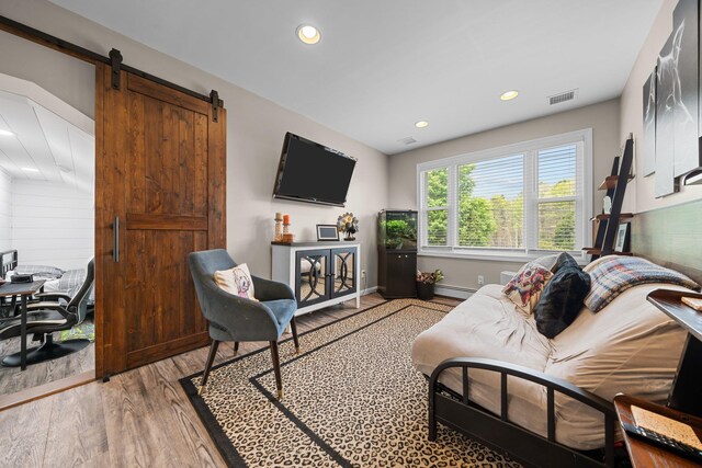 142 Rte 25a, Shoreham, NY 11786 - living area with light wood finished floors, baseboard heating, recessed lighting, a barn door, and baseboards