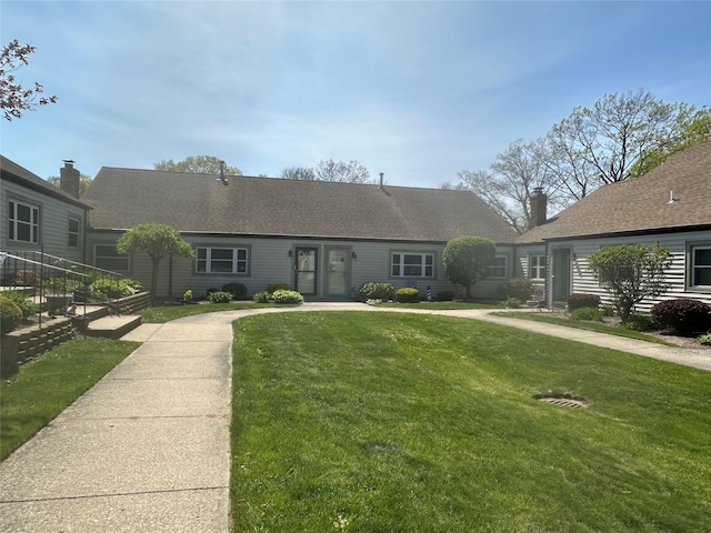 ranch-style home featuring roof with shingles and a front lawn