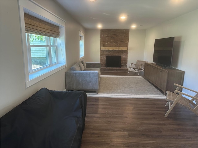 living area featuring a brick fireplace, dark wood-type flooring, and recessed lighting