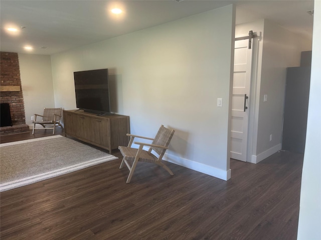 living area with baseboards, a brick fireplace, and dark wood-style floors