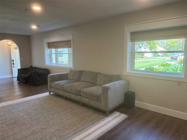 living area with recessed lighting, baseboards, arched walkways, and dark wood-style floors