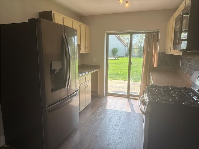 kitchen with range with gas stovetop, white cabinetry, stainless steel fridge, wood finished floors, and tasteful backsplash